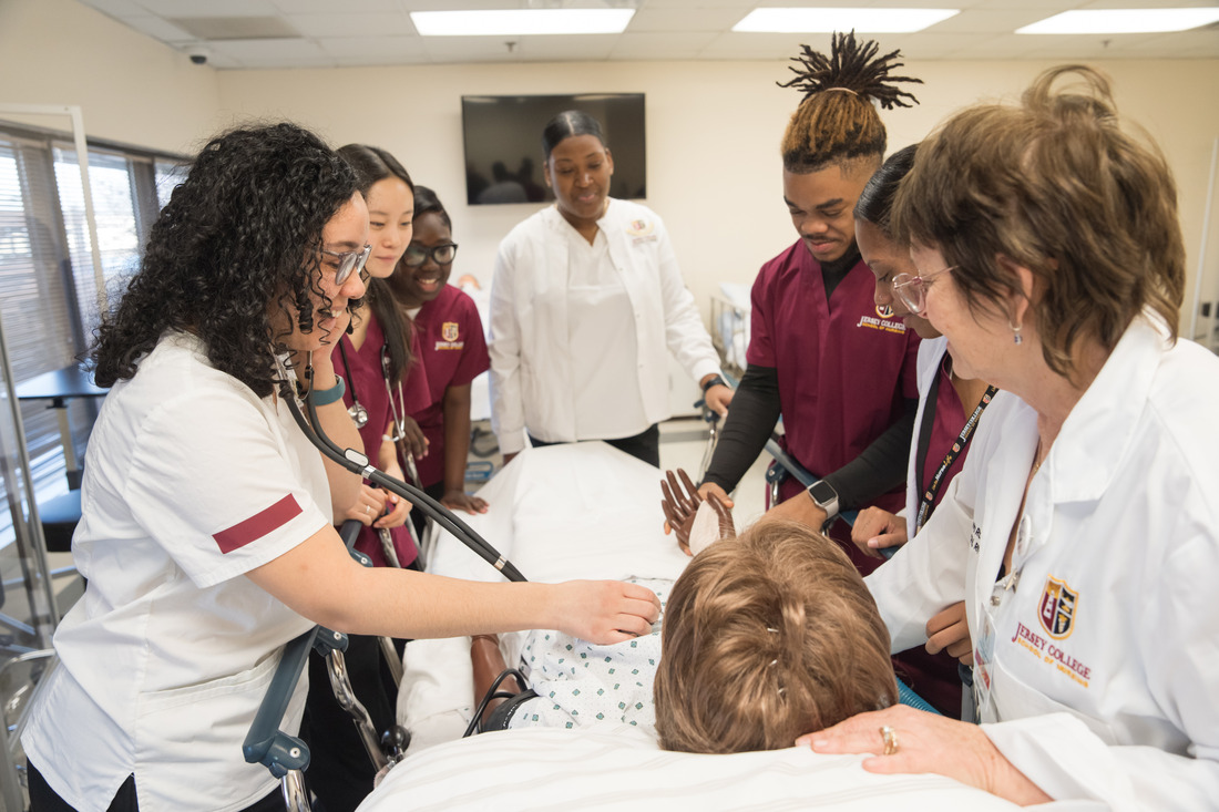 A group of nursing students and their professor practice bedside medical procedures on a patient simulator in a well-equipped skills lab.